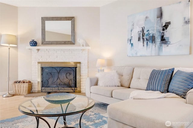 living room featuring a brick fireplace and wood finished floors