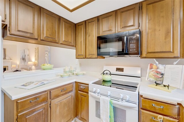 kitchen featuring brown cabinetry, a peninsula, black microwave, white range with electric cooktop, and light countertops