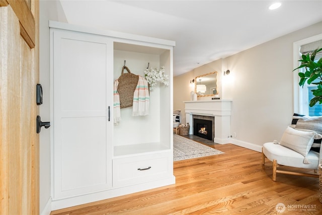 interior space featuring light wood-type flooring, a fireplace with flush hearth, baseboards, and recessed lighting