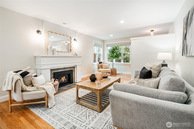 living room with recessed lighting, baseboards, a tiled fireplace, and light wood-type flooring