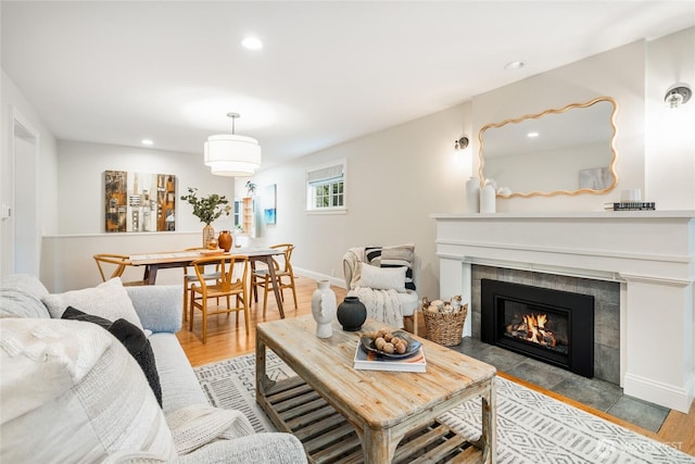 living area featuring baseboards, a fireplace, recessed lighting, and wood finished floors