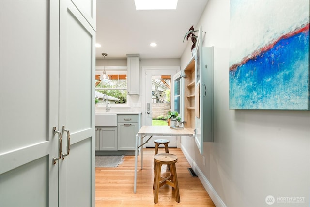 corridor featuring light wood-style floors, recessed lighting, a sink, and visible vents