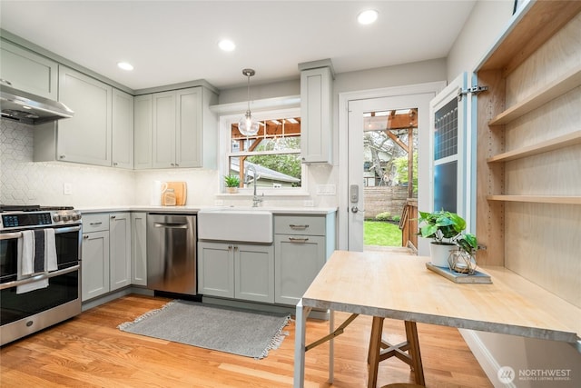 kitchen featuring gray cabinetry, light wood-style floors, stainless steel appliances, and under cabinet range hood