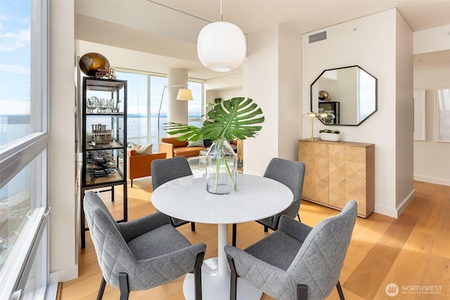 dining area with baseboards, visible vents, and light wood-style floors