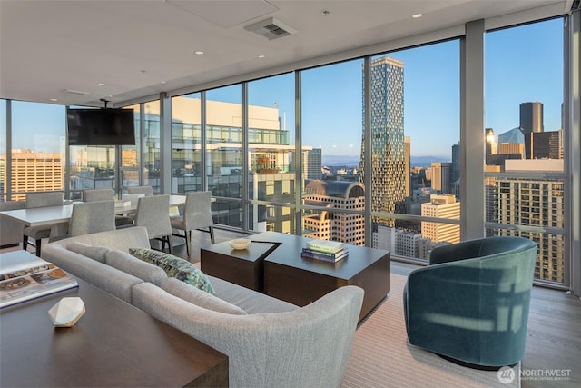 living room with expansive windows, wood finished floors, and a healthy amount of sunlight