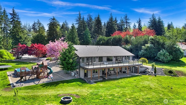 back of house featuring a lawn, a playground, a patio area, and a deck