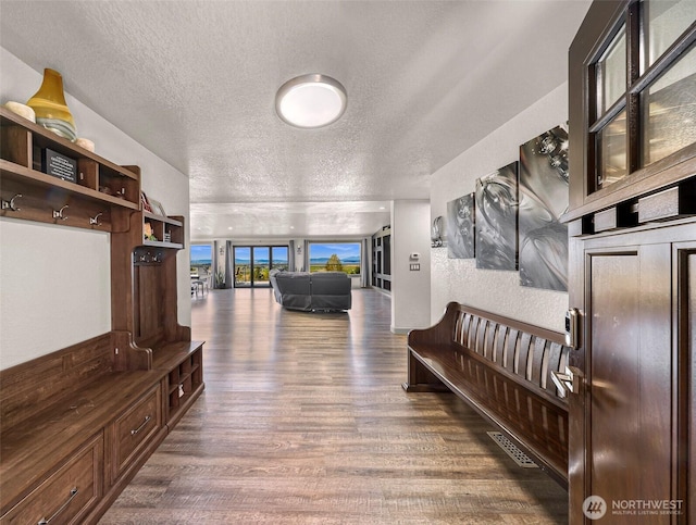 hallway with a textured ceiling and wood finished floors