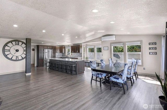 dining space with baseboards, a wall unit AC, dark wood-style floors, and vaulted ceiling