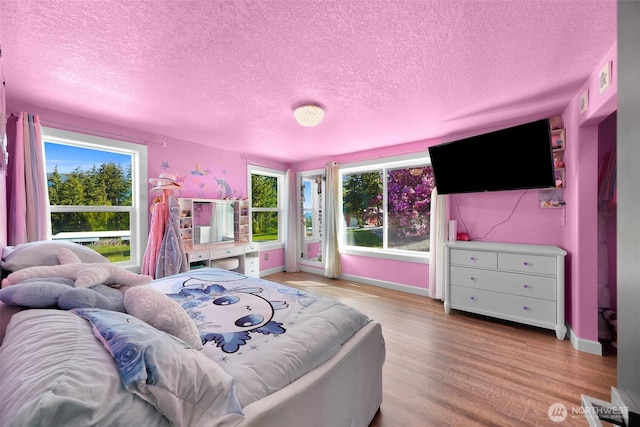 bedroom featuring baseboards, a textured ceiling, and wood finished floors