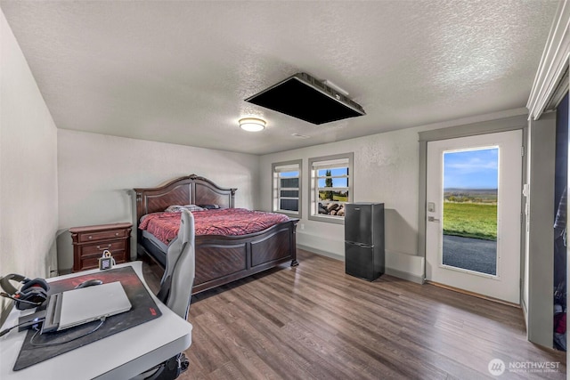 bedroom with baseboards, a textured ceiling, and wood finished floors