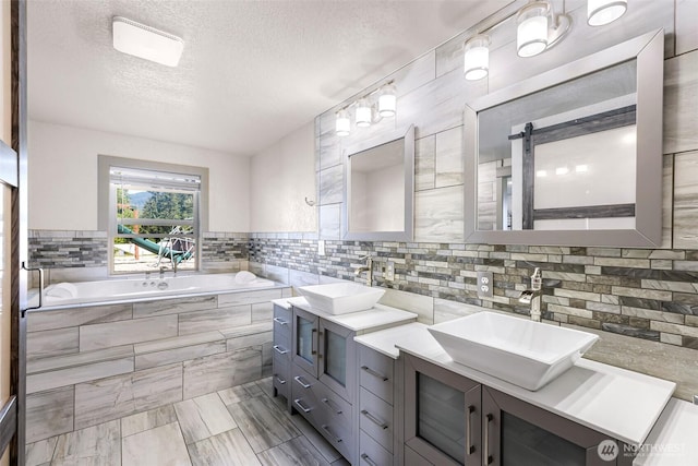 bathroom with double vanity, a textured ceiling, a sink, and a garden tub