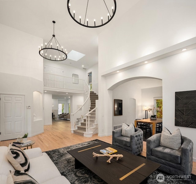9732 Slater Ave NE, Kirkland, WA 98033 - living area featuring arched walkways, a chandelier, wood finished floors, a towering ceiling, and visible vents
