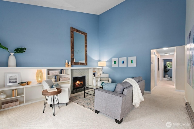 carpeted living room with baseboards, a fireplace with flush hearth, and a towering ceiling