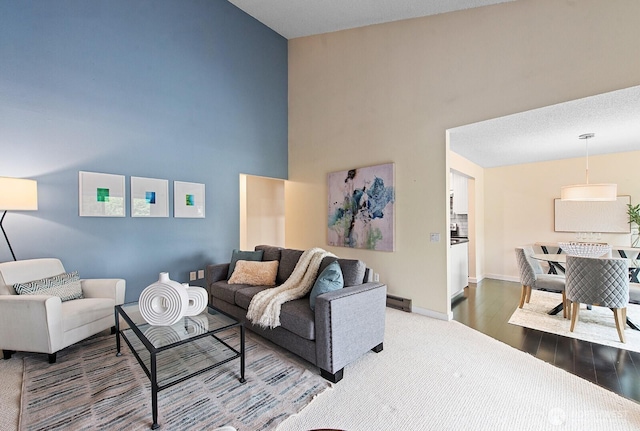 living room with baseboards, a high ceiling, baseboard heating, and wood finished floors