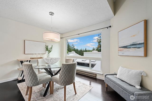 dining room with wood-type flooring, a textured ceiling, and baseboards