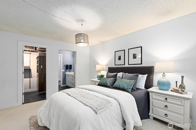 bedroom with connected bathroom, carpet, a textured ceiling, and a walk in closet