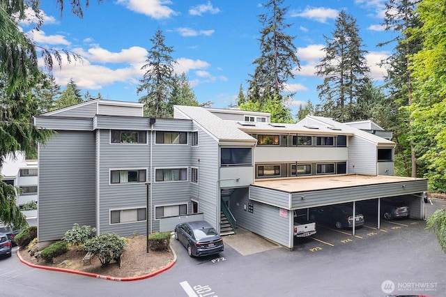 view of building exterior featuring stairway and covered and uncovered parking