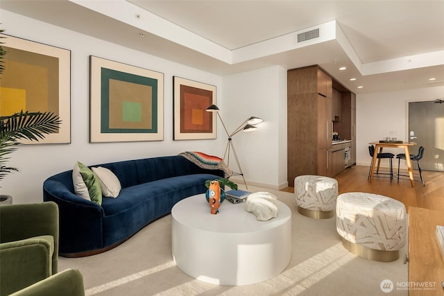 living room featuring visible vents, wood finished floors, baseboards, a tray ceiling, and recessed lighting