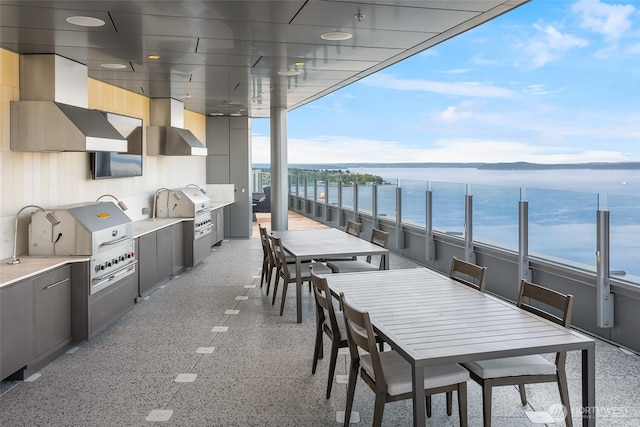 view of patio featuring outdoor dining area, a water view, and an outdoor kitchen
