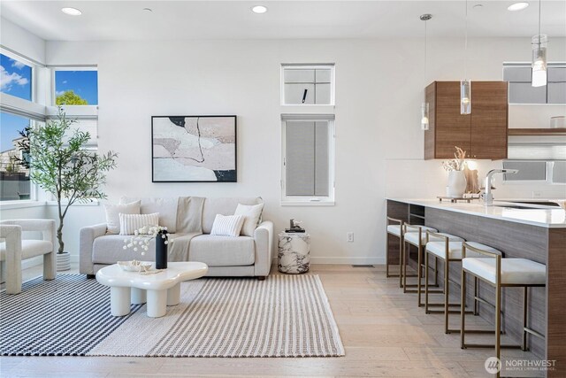 living area with recessed lighting, baseboards, and light wood-type flooring