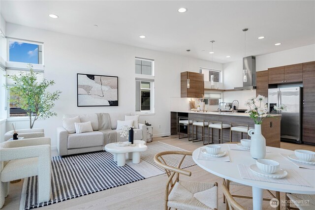living area with recessed lighting, light wood-style floors, and baseboards