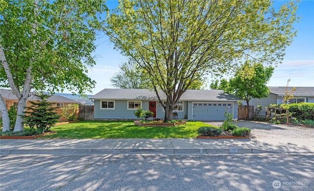 ranch-style home with a garage, fence, driveway, and a front yard