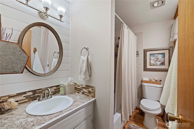 bathroom featuring vanity, wood finished floors, toilet, shower / bathtub combination with curtain, and tasteful backsplash