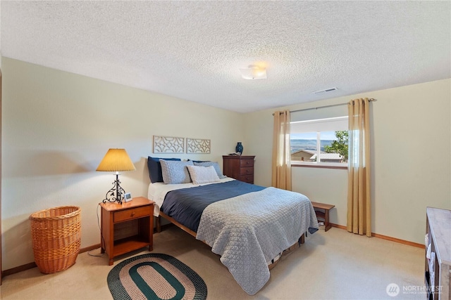 bedroom featuring baseboards, light carpet, a textured ceiling, and visible vents