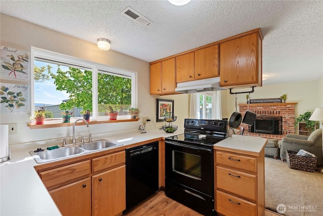 kitchen with visible vents, a sink, black appliances, a peninsula, and under cabinet range hood