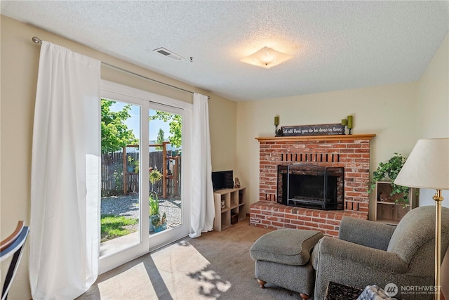 carpeted living room with visible vents, a textured ceiling, and a brick fireplace