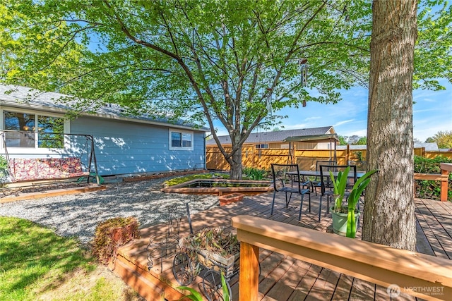 view of yard with outdoor dining area, a wooden deck, a fenced backyard, and a garden