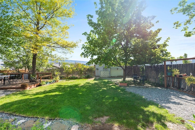 view of yard featuring a fenced backyard, an outbuilding, a deck, and a storage shed