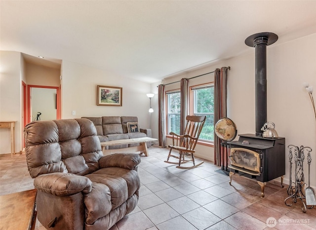 living room featuring baseboards, a wood stove, and light tile patterned floors