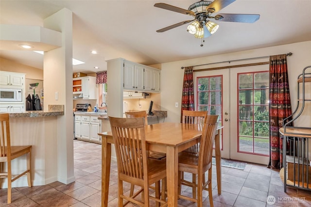 dining space with light tile patterned floors, plenty of natural light, and a ceiling fan