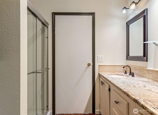 bathroom featuring vanity, a textured wall, and a stall shower