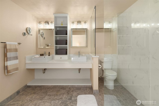 full bath with baseboards, a sink, double vanity, and toilet