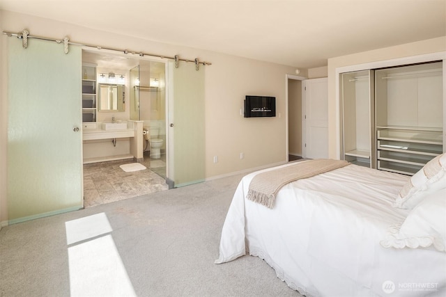 carpeted bedroom featuring a closet, a sink, baseboards, and connected bathroom