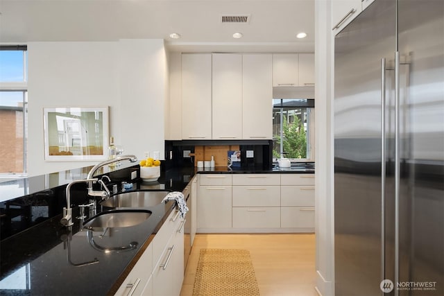 kitchen with visible vents, modern cabinets, white cabinetry, high end fridge, and light wood-style flooring