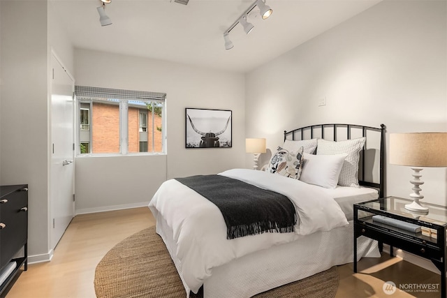 bedroom featuring baseboards, visible vents, track lighting, and light wood finished floors
