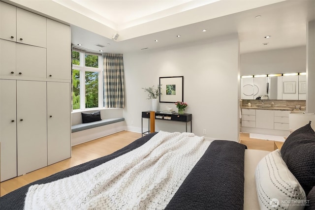 bedroom with recessed lighting, ensuite bath, and light wood-type flooring