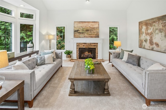 living area with carpet, lofted ceiling, a wealth of natural light, and a fireplace