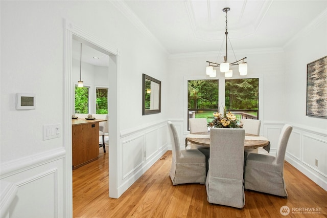 dining space featuring a chandelier, a healthy amount of sunlight, light wood finished floors, and a decorative wall