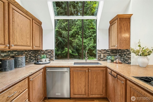 kitchen with stainless steel dishwasher, black gas cooktop, a sink, and tasteful backsplash