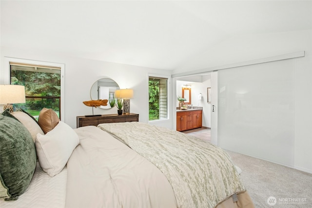 bedroom featuring light colored carpet, connected bathroom, vaulted ceiling, and multiple windows