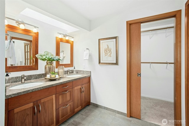full bathroom with a walk in closet, baseboards, and a sink