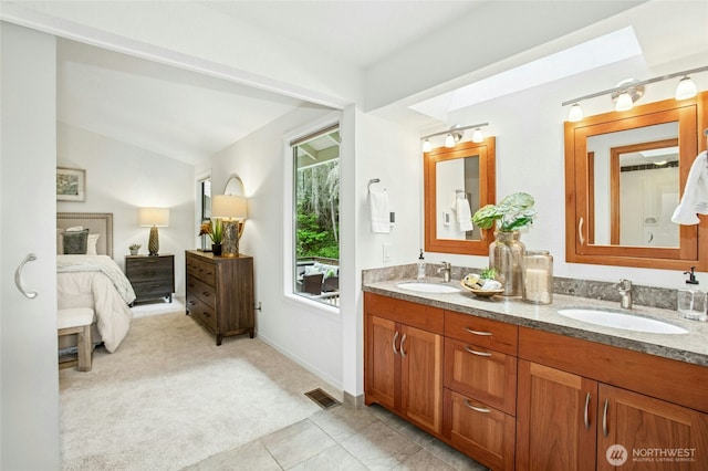 ensuite bathroom with double vanity, vaulted ceiling, a sink, and ensuite bathroom