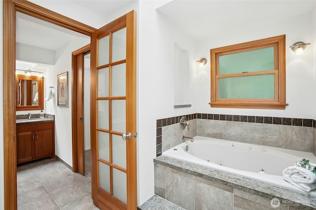 full bath with vanity and a jetted tub