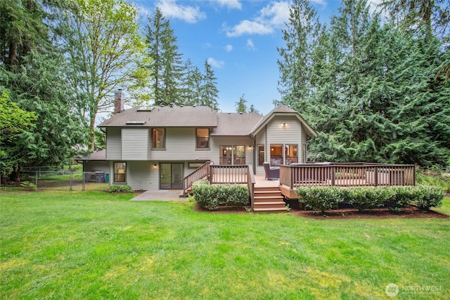 rear view of house featuring a chimney, french doors, a deck, fence, and a yard