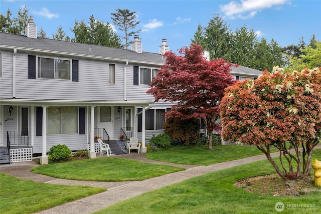 view of front of home featuring a chimney, a porch, and a front lawn