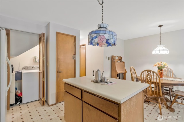 kitchen featuring washer / dryer, light floors, pendant lighting, and light countertops